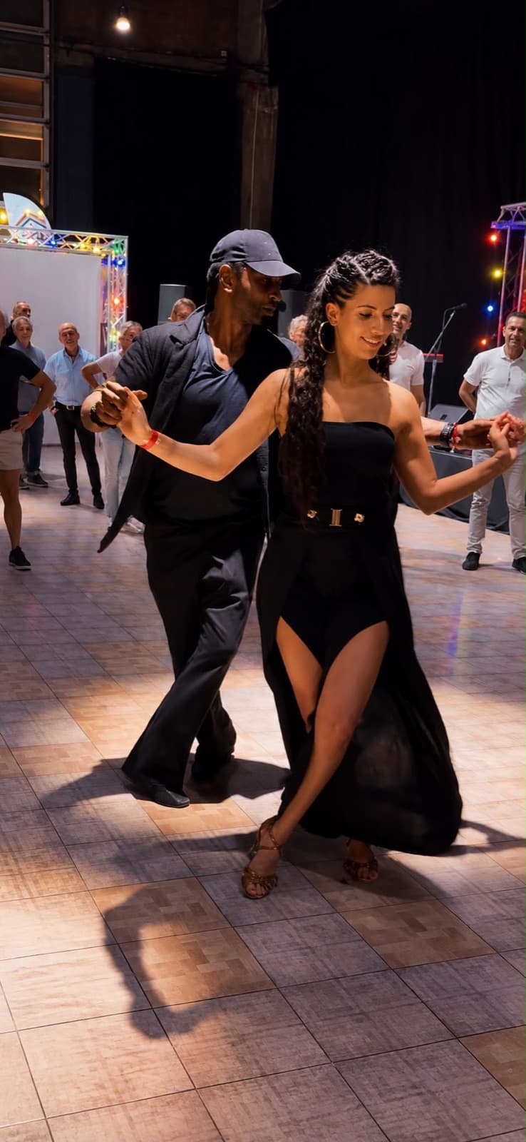 Mike O danse en couple lors d'une soirée, le public autour de la piste