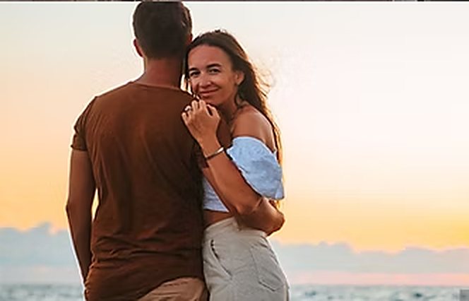 Couple face à la mer au coucher du soleil