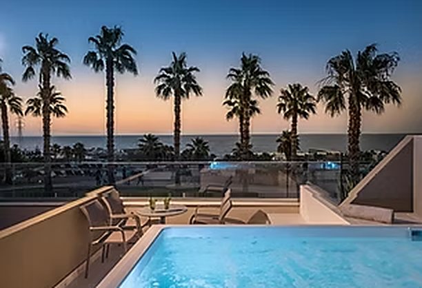 Terrace with pool and palm trees at sunset