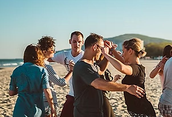 Groep die in koppels danst op een strand